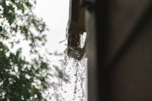 Rainwater draining through a metal gutter during a storm