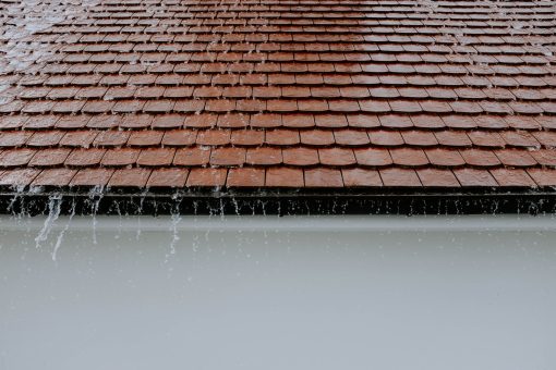 Heavy rain cascading over a roof edge toward the gutters