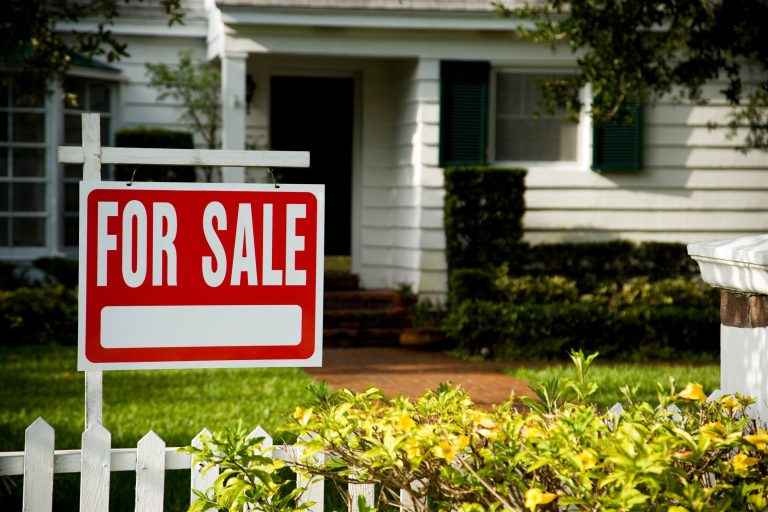 For sale sign in the front yard of a house with a picket fence