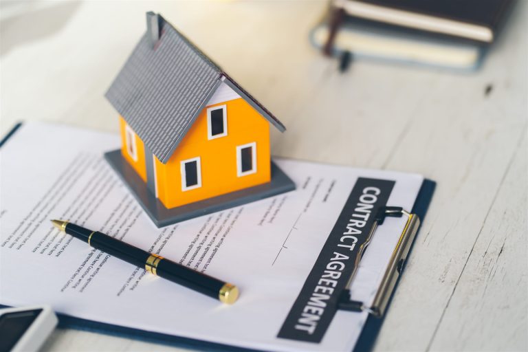 Model house on a contract agreement with a pen on a desk