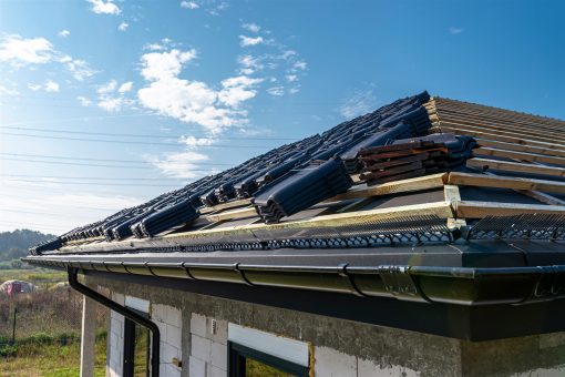New roof being laid in dark tiles with a gutter already fixed along the eave