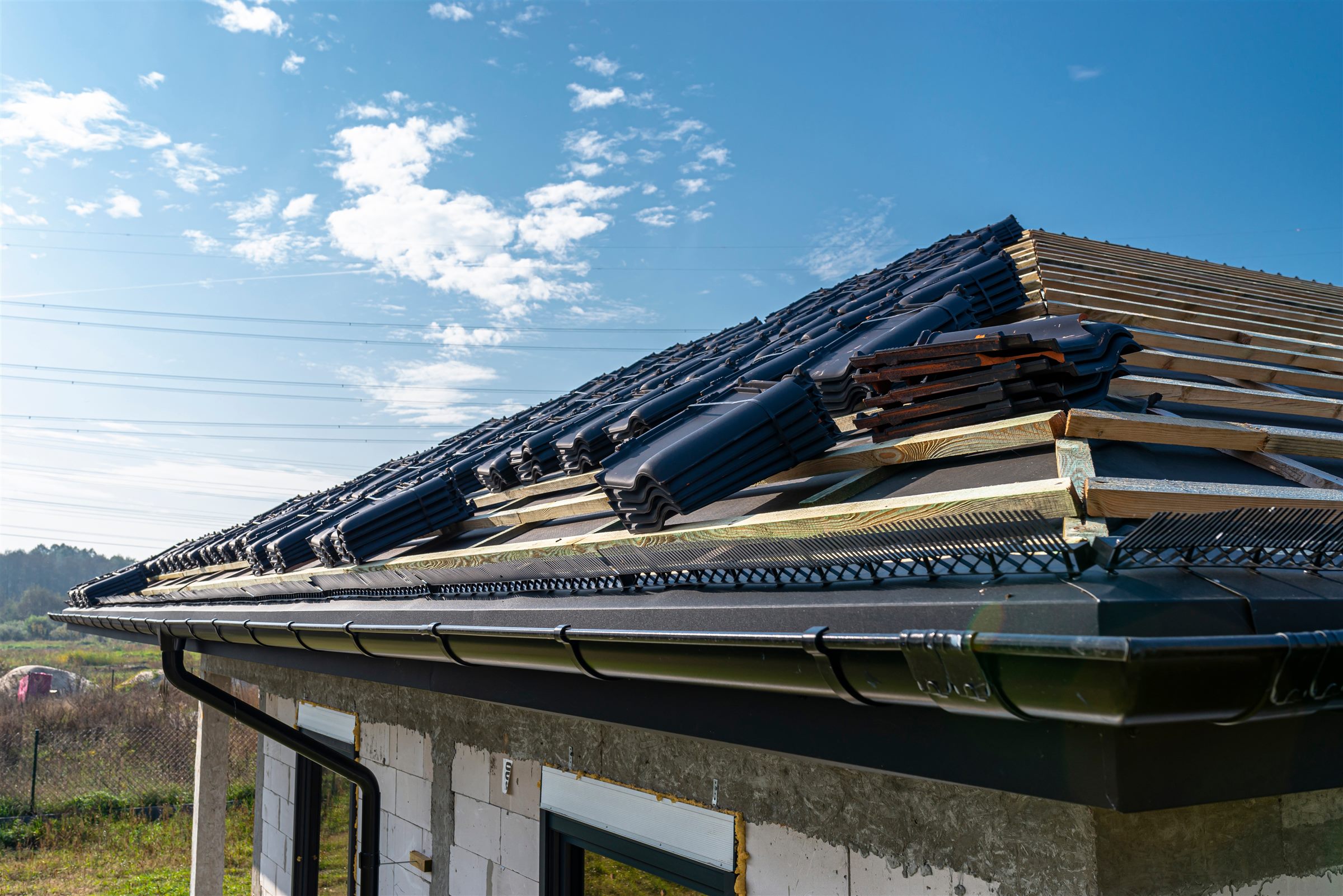 New roof being laid in dark tiles with a gutter already fixed along the eave